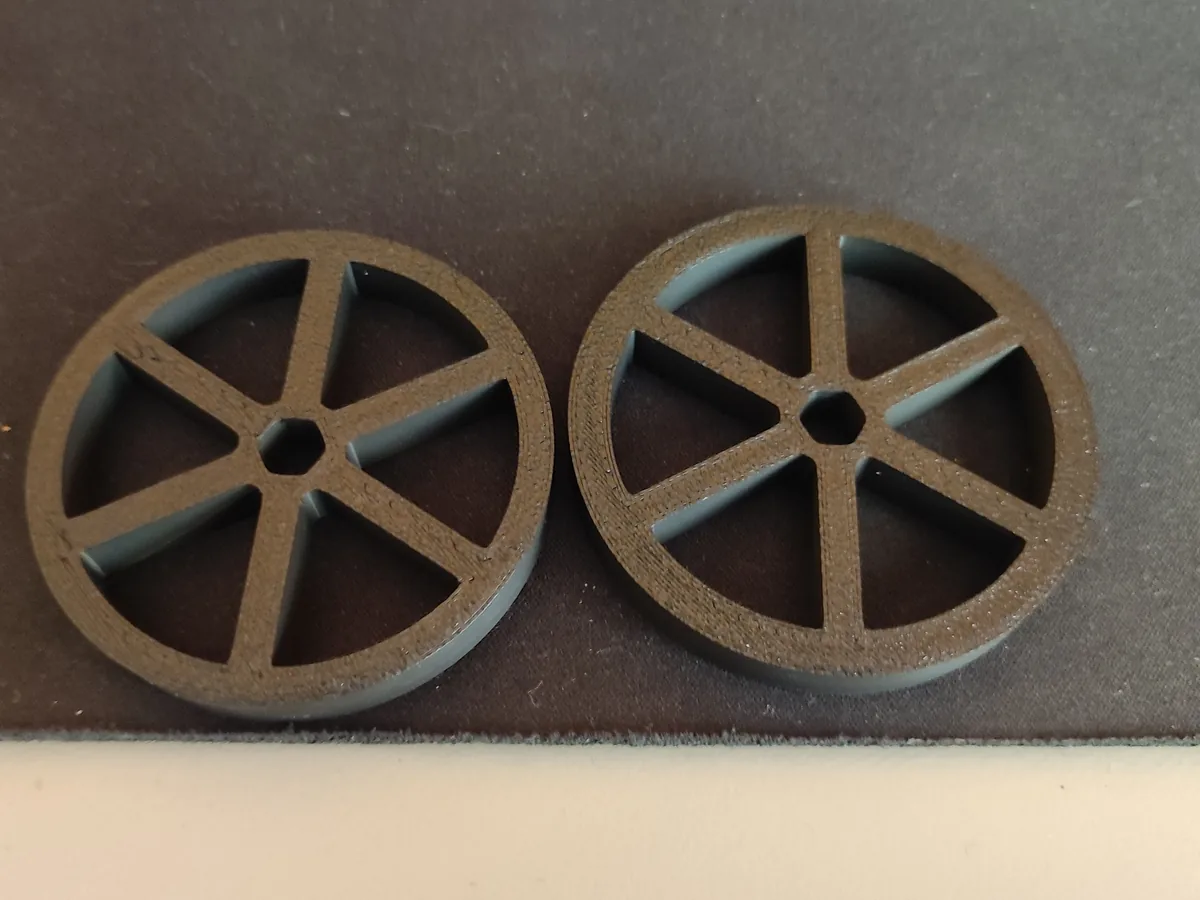 Two 3D-printed spoked discs that mount on the transfer shafts