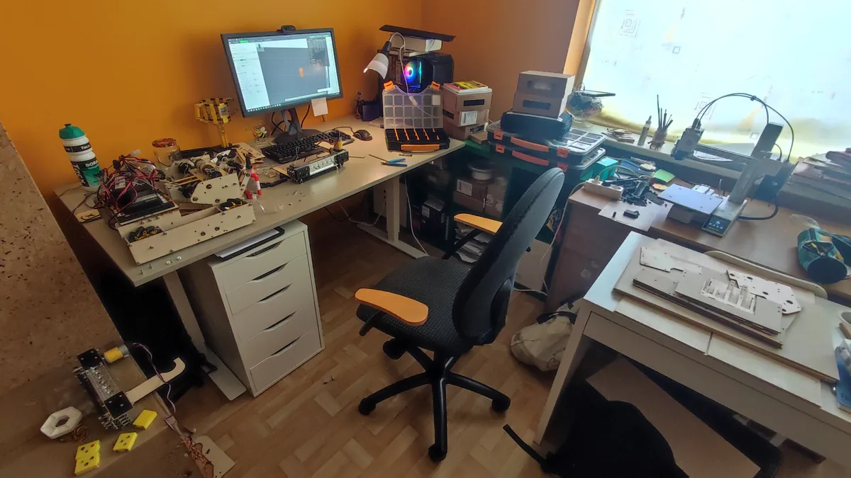 A bedroom used as a workshop, robot parts and subassemblies spread over two desks